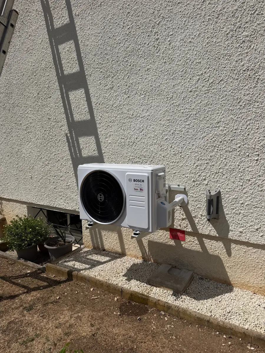Groupe extérieur de climatisation Bosch posé par F2C contre une façade crépie de maison récente