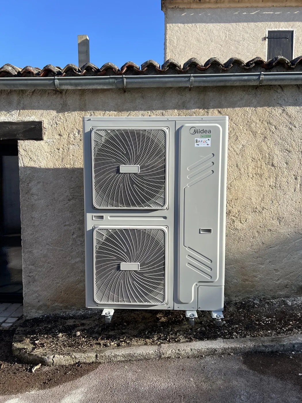 Groupe extérieur de pompe à chaleur Midea posé contre une façade, installé par F2C