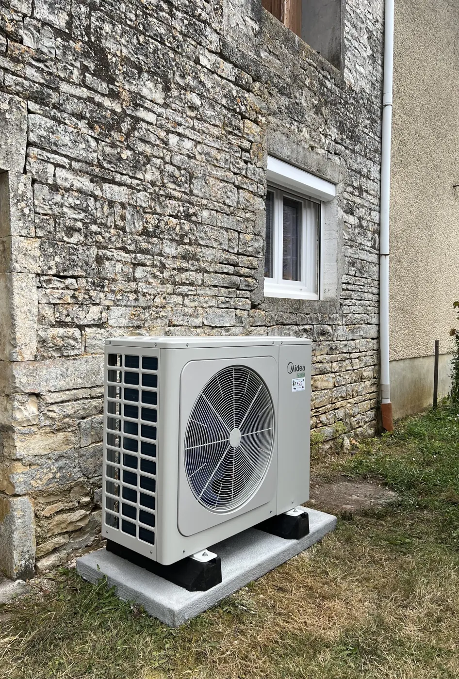 Pompe à chaleur Midea installée par F2C contre le mur en pierre d'une maison de campagne